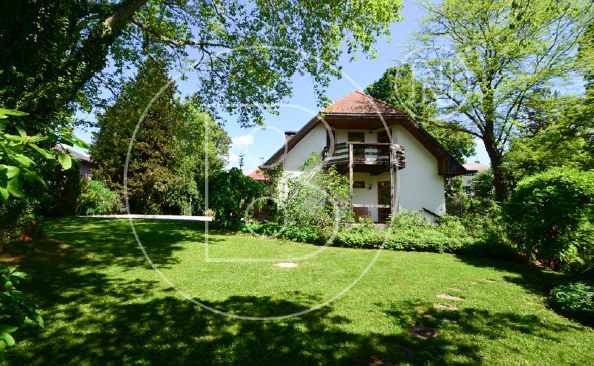 Charmantes Einfamilienhaus umgeben von einem gepflegten, grünen Garten mit altem Baumbestand.