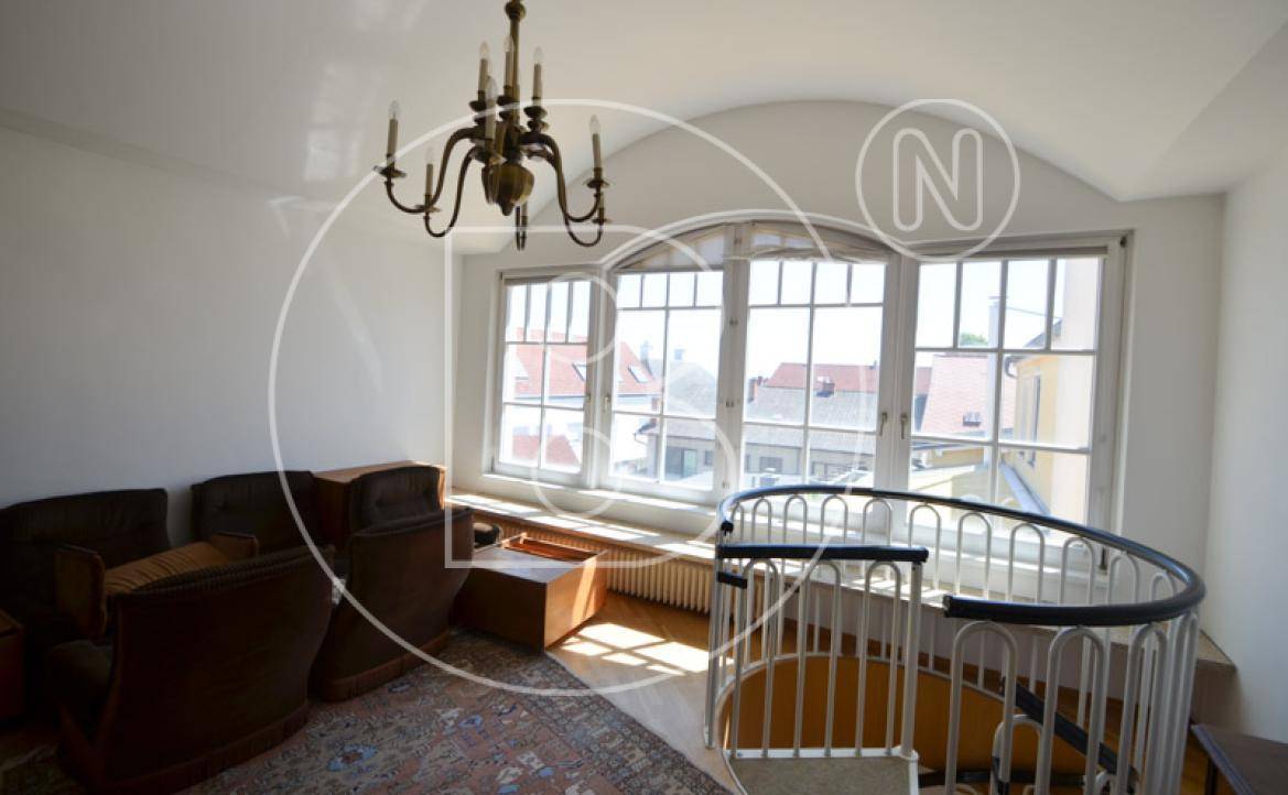 Gemütlicher Wohnbereich mit Sofa, Kronleuchter, großen Fenstern und Blick auf die Umgebung.