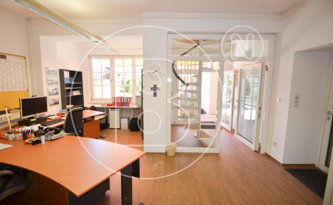 Offener Bürobereich mit Schreibtischen und einer eleganten Wendeltreppe im Hintergrund.