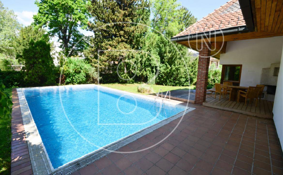 Großer Swimmingpool mit gefliester Terrasse und angrenzendem Gartenbereich.