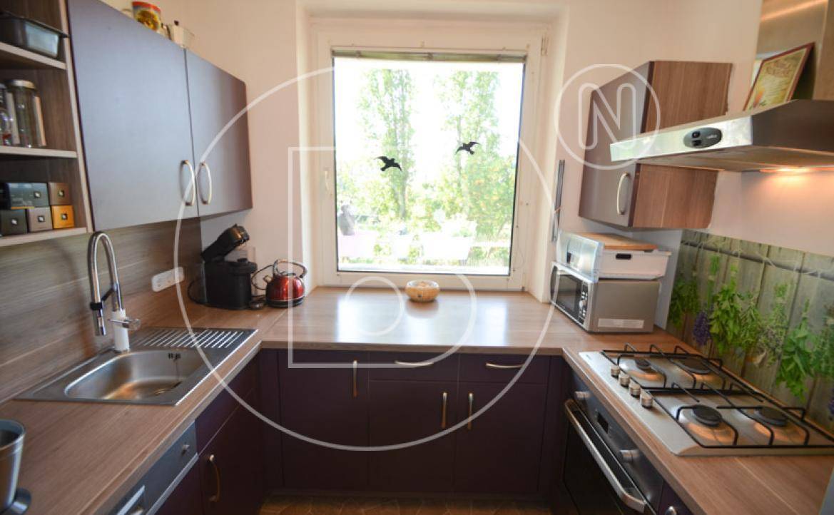 Funktionale Küche mit Holz-Arbeitsplatten, Gasherd und Fenster mit Blick ins Grüne.