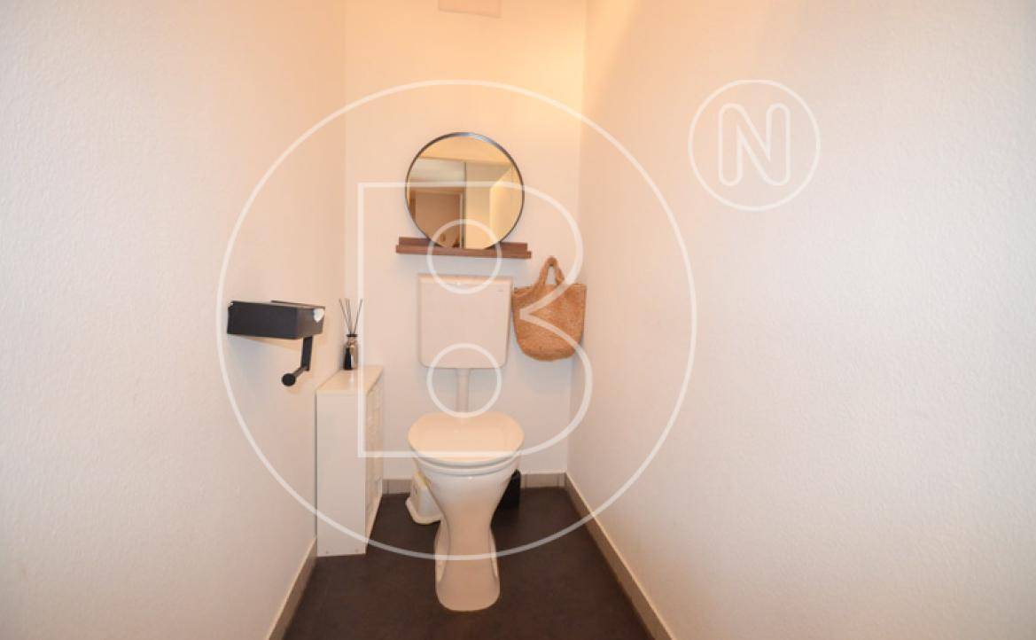 Separates Gäste-WC mit Toilette und kleinem runden Spiegel.