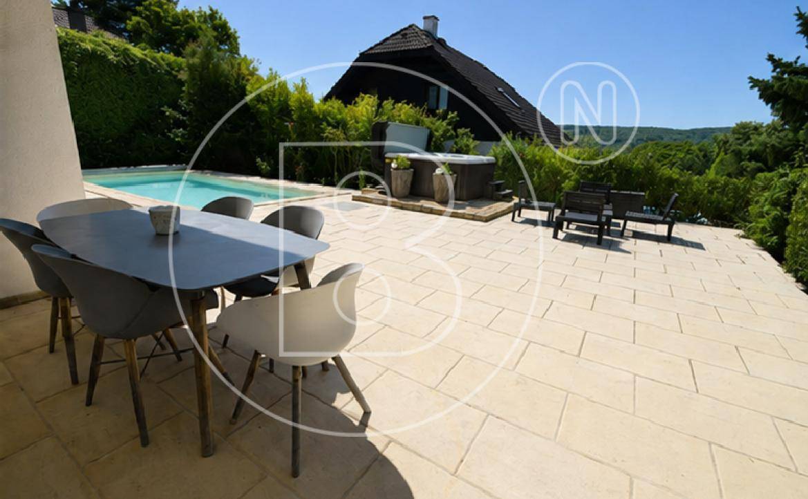 Geräumige Terrasse mit Essbereich im Freien, umgeben von Grün und mit Blick in die Ferne.