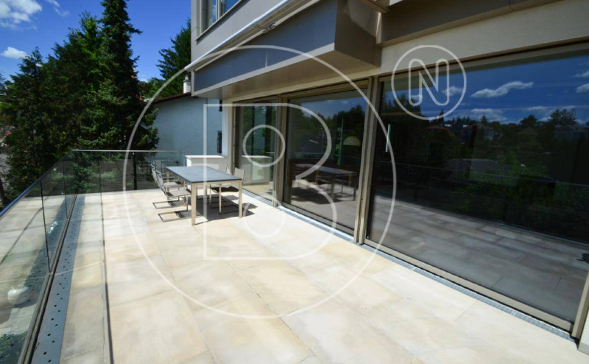 Helle Terrasse mit großen Schiebetüren zum Innenbereich und modernem Glasgeländer.