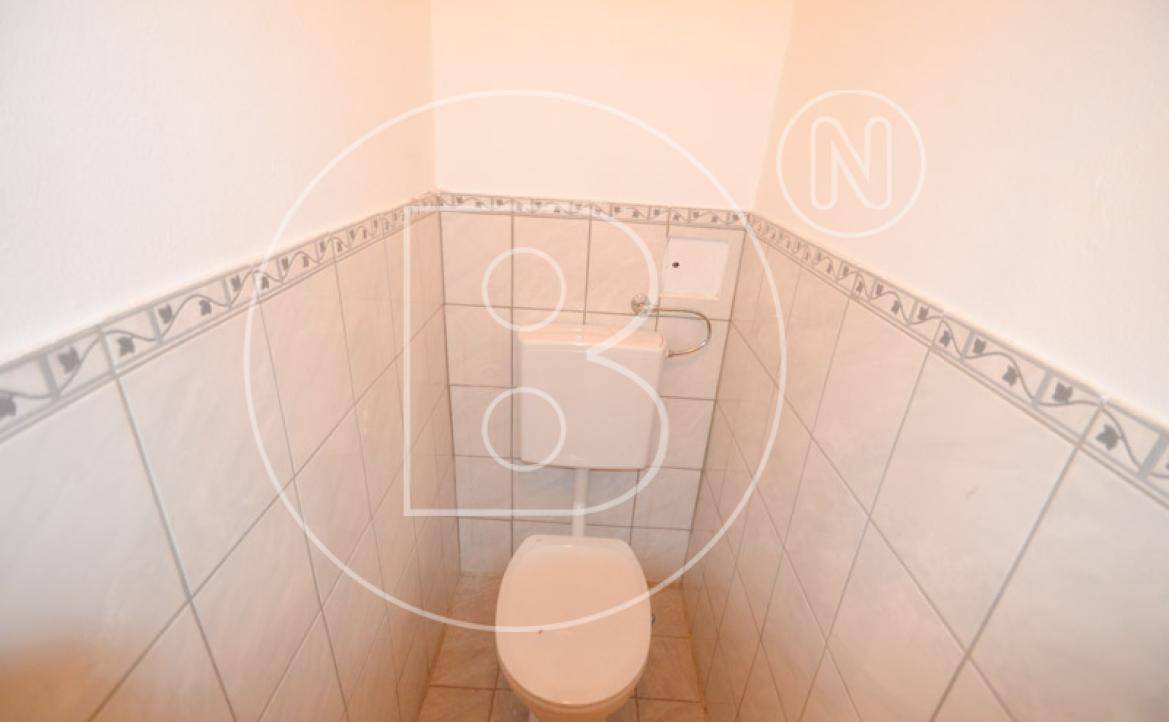 Separate Toilette mit Fliesen an den Wänden und einem einfachen WC, sauber und funktional.