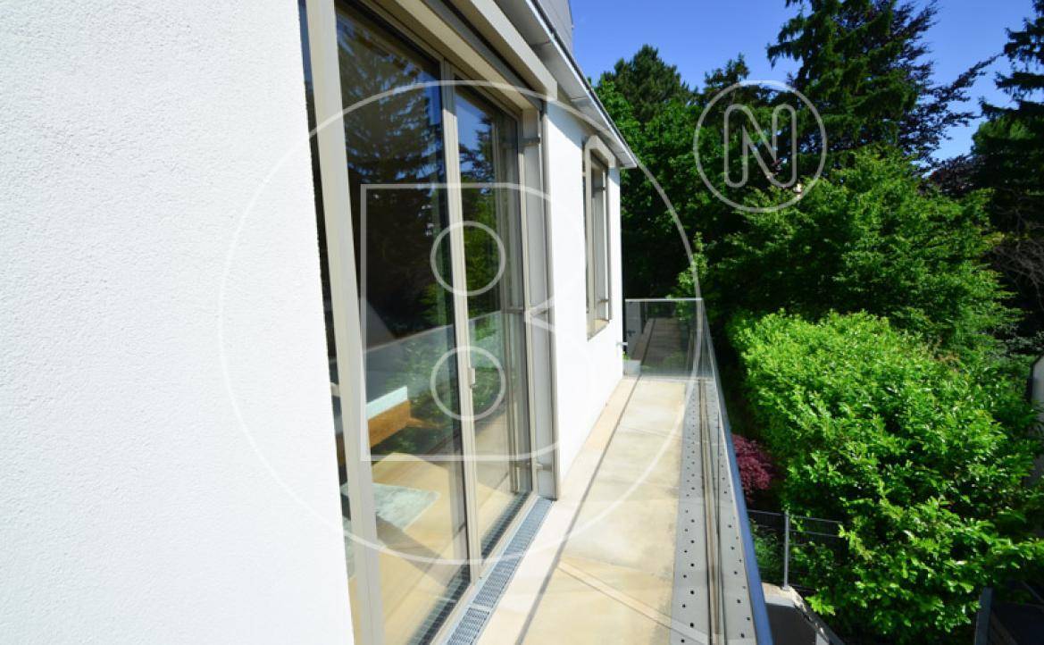 Langer Balkon mit Glasgeländer und Blick ins Grüne, zugänglich vom Schlafzimmer.