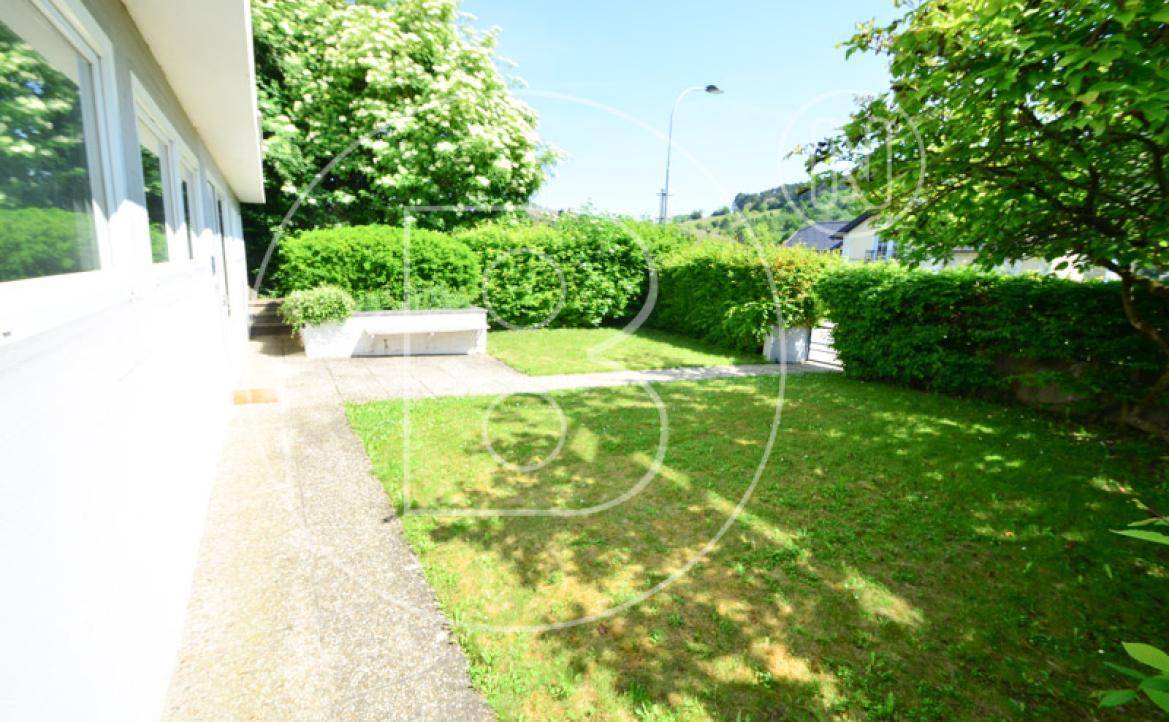 Seitlicher Gartenbereich mit einer Steinbank und gepflegten Hecken, ideal zum Verweilen.