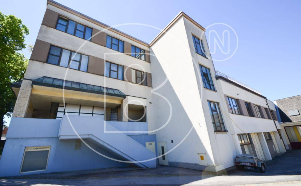 Seitenansicht des Gebäudes mit moderner Architektur, großen Fenstern und Außentreppe.
