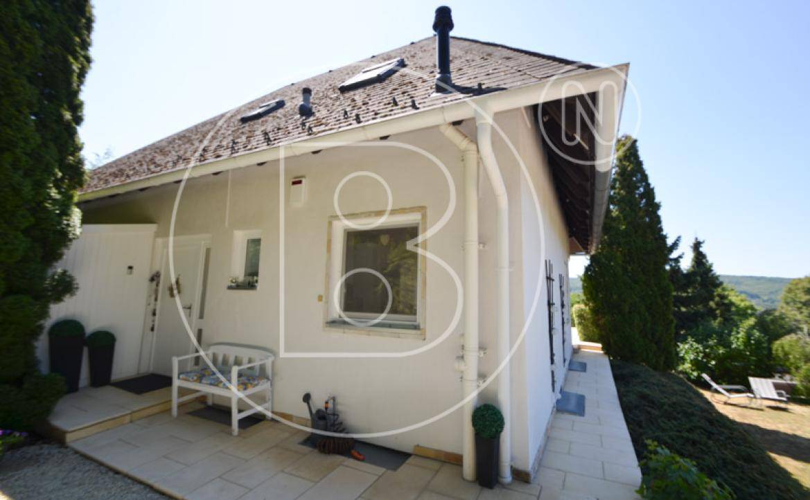Seitliche Terrasse des Hauses mit Sitzbank und Blick auf die grüne Umgebung.