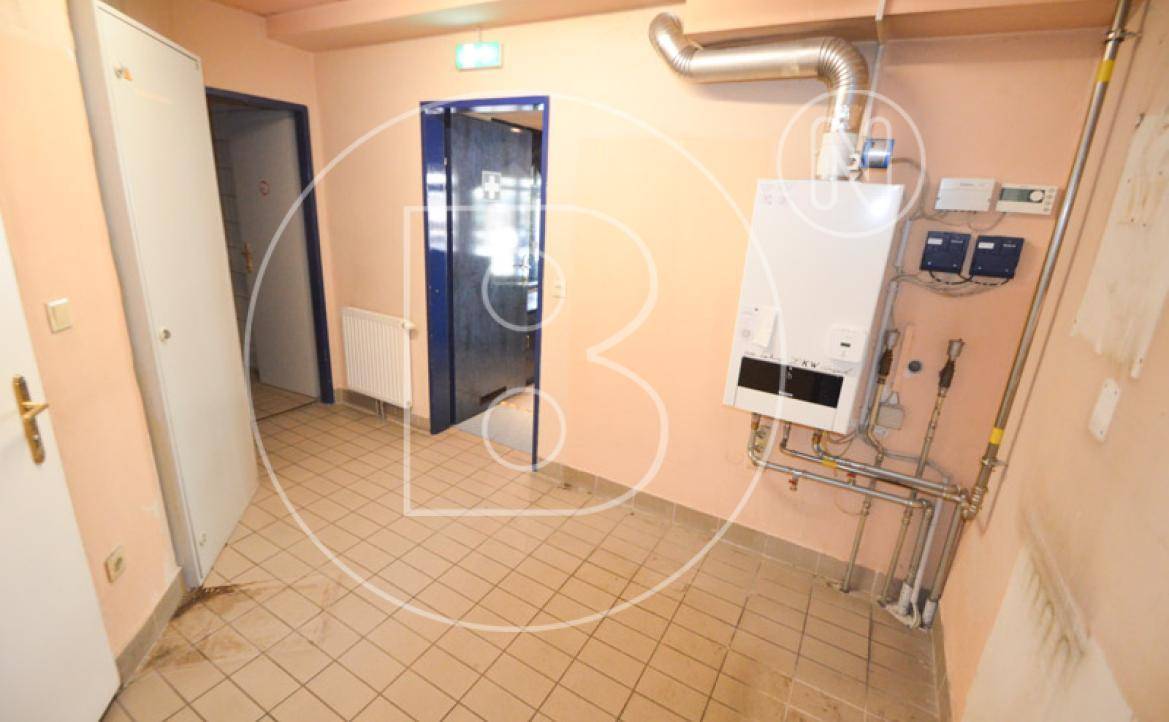 Technikraum mit Heizungsanlage, Rohren und Fliesenboden, dient der Versorgung des Gebäudes.