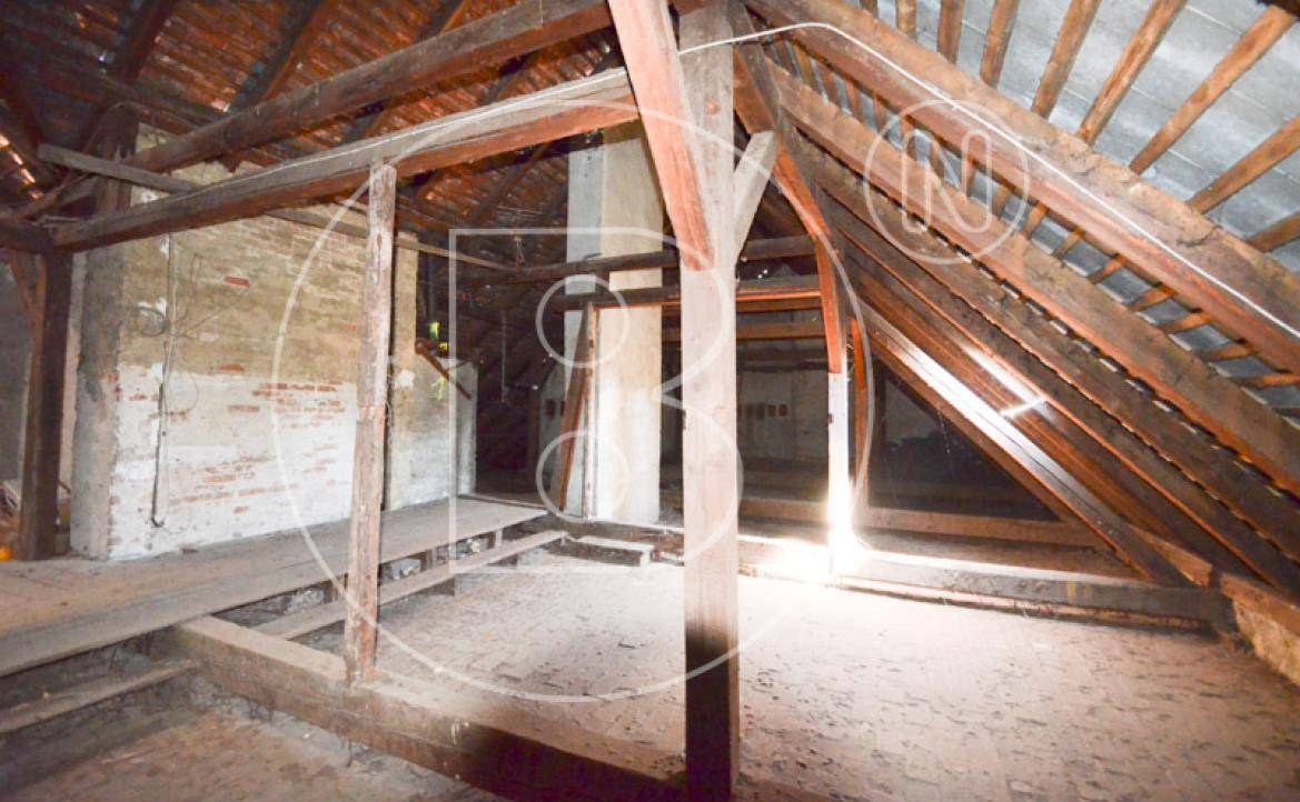 Unausgebauter Dachboden mit freiliegenden Holzbalken und Ziegelwänden, ideal für zukünftige Renovierungsprojekte.