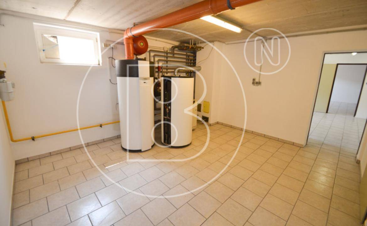 Technikraum im Keller mit Heizungsanlage, Warmwasserspeicher und Fliesenboden.