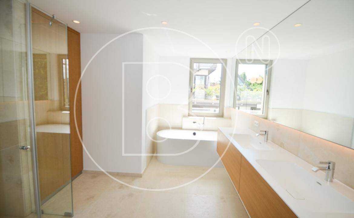 Helles Badezimmer mit Badewanne, Doppelwaschbecken und großer Fensterfront.