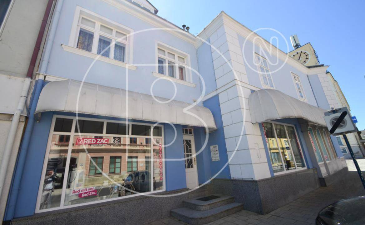 Eingangsbereich eines Geschäfts mit blauer Fassade und großen Schaufenstern in der Stadt.