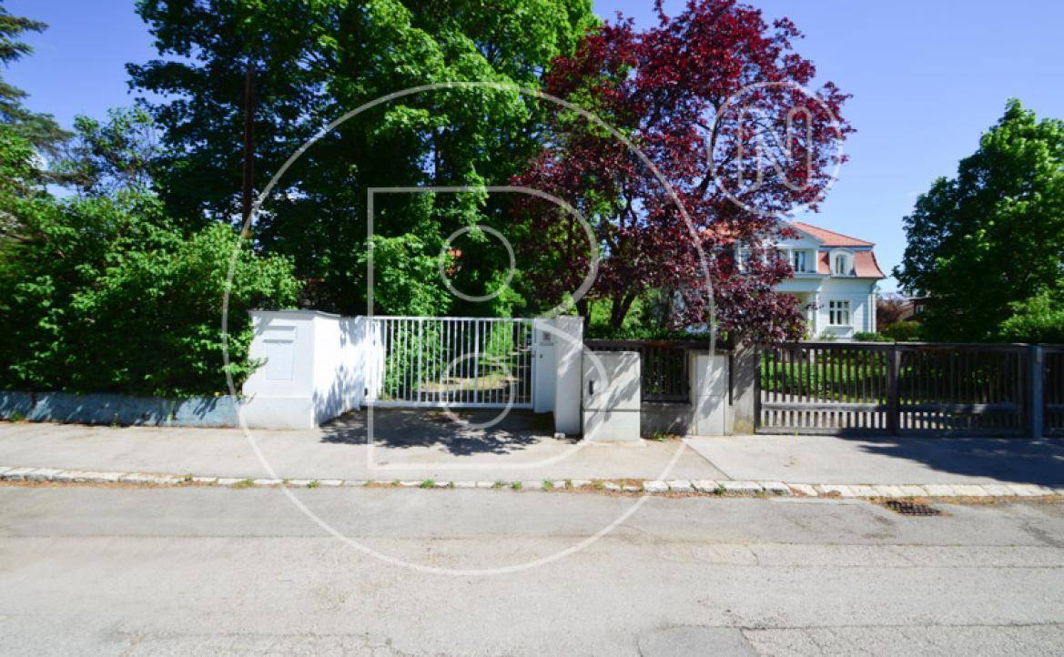 Straßenansicht des Anwesens mit Einfahrtstor und einem charmanten Haus im Hintergrund.