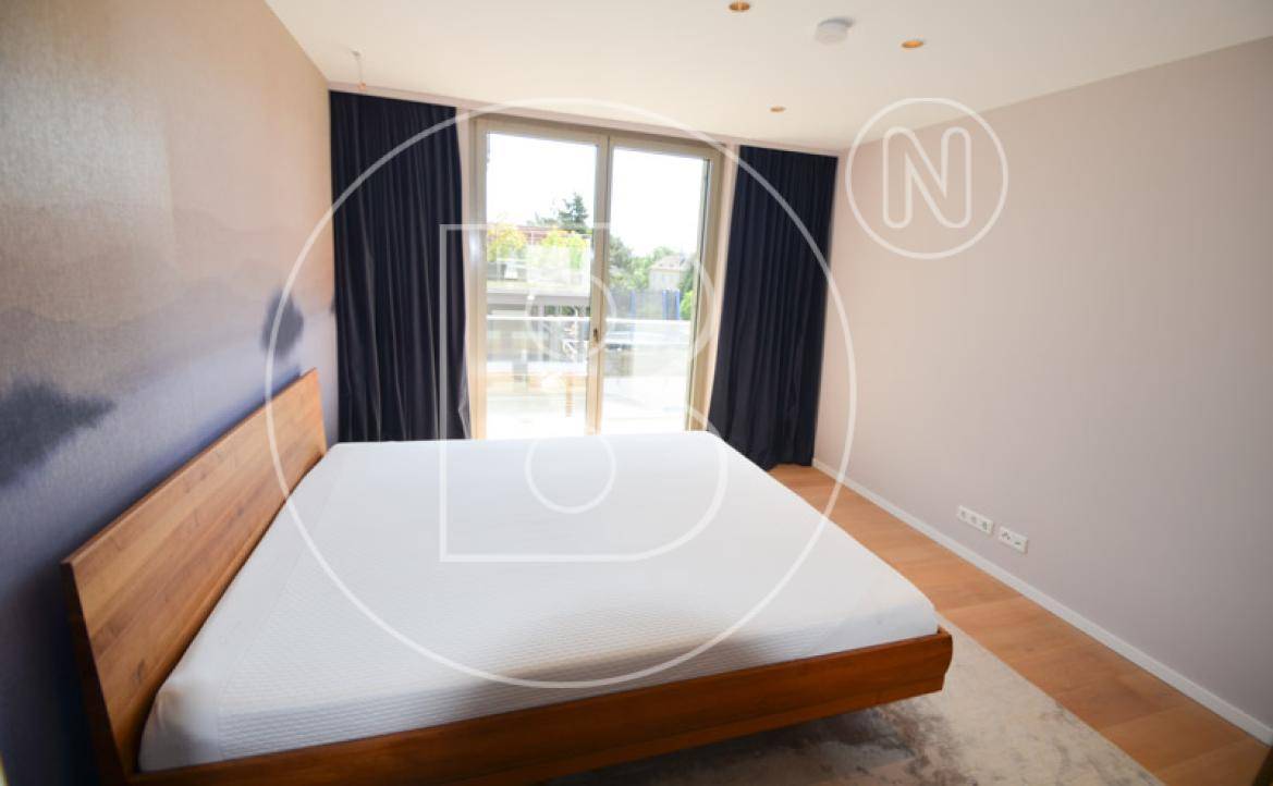Helles Schlafzimmer mit Holzbett, Parkettboden und Zugang zu einem Balkon.