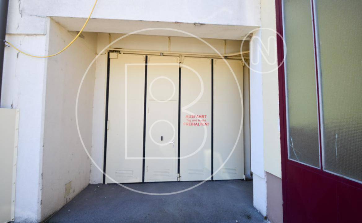 Großes Garagentor mit Warnhinweis "Ausfahrt freihalten" an der Gebäuderückseite.
