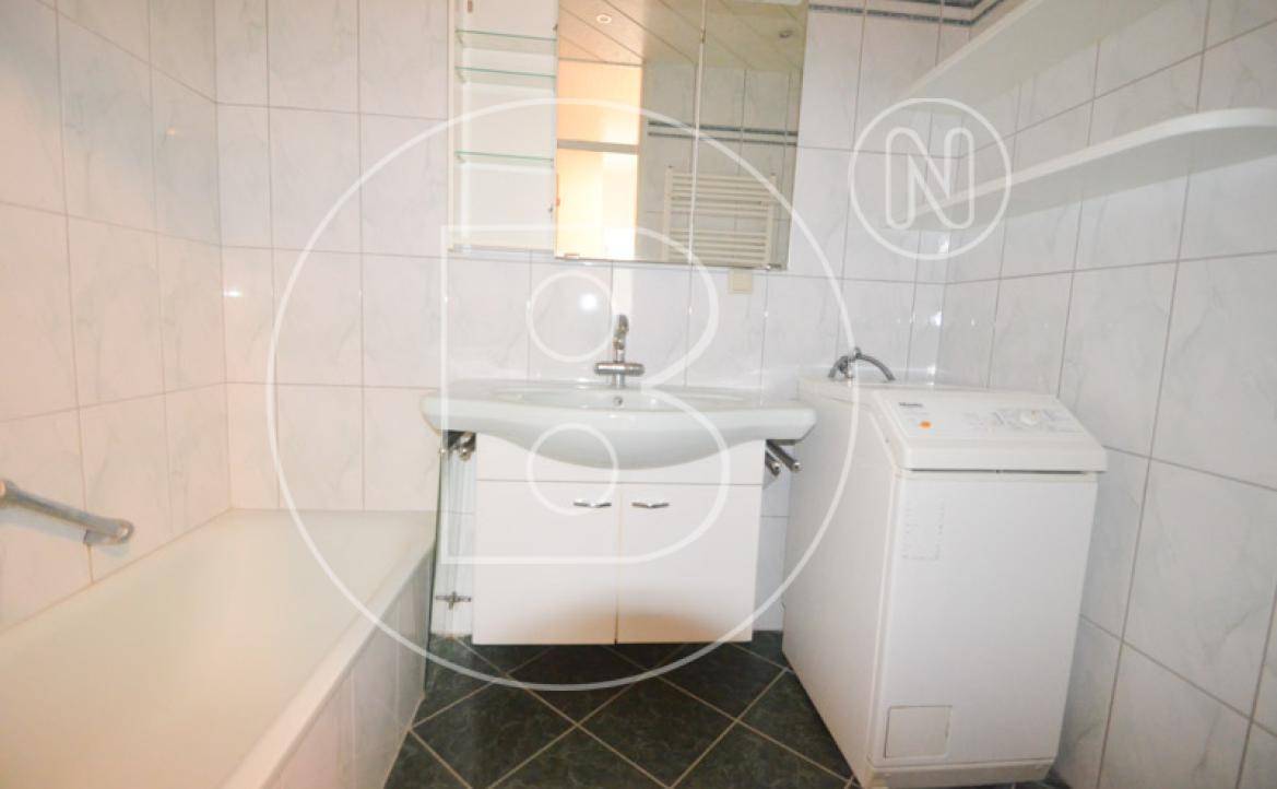 Badezimmer mit Badewanne, Waschbecken, Spiegelschrank und integrierter Waschmaschine.