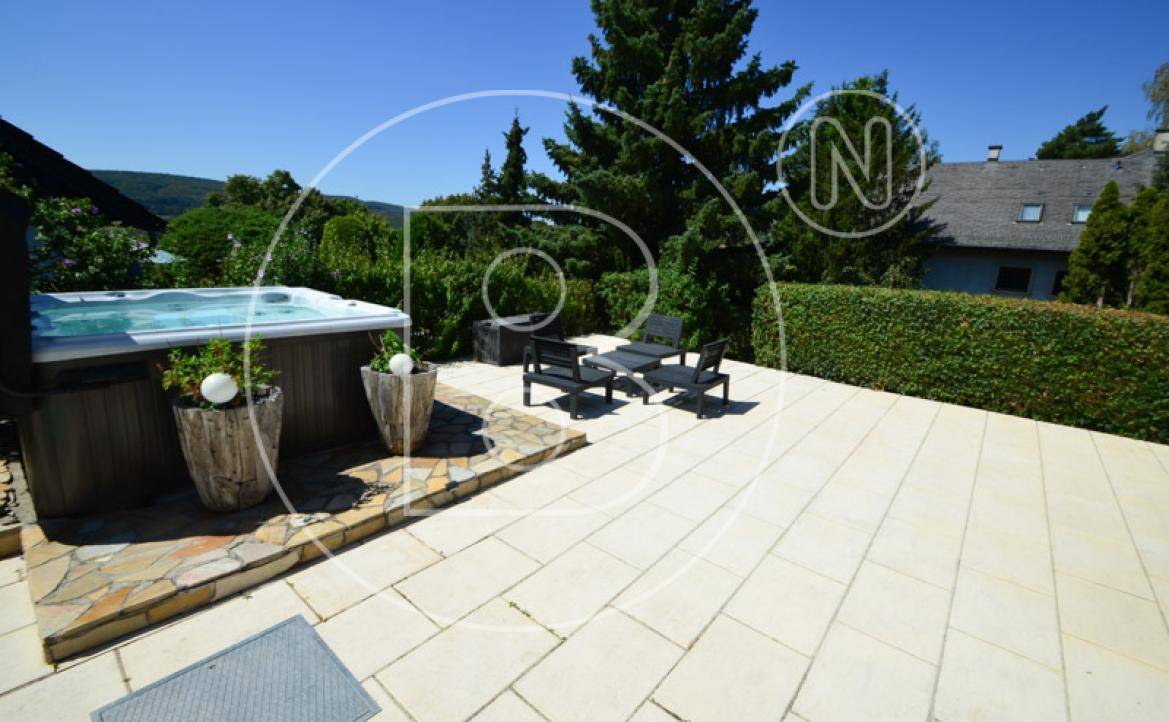 Whirlpool auf der Terrasse, umgeben von üppigem Grün und mit weiteren Sitzgelegenheiten im Freien.