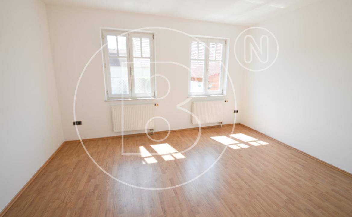 Schlafzimmer mit Laminatboden, weißen Wänden und zwei Fenstern für natürliche Belichtung.