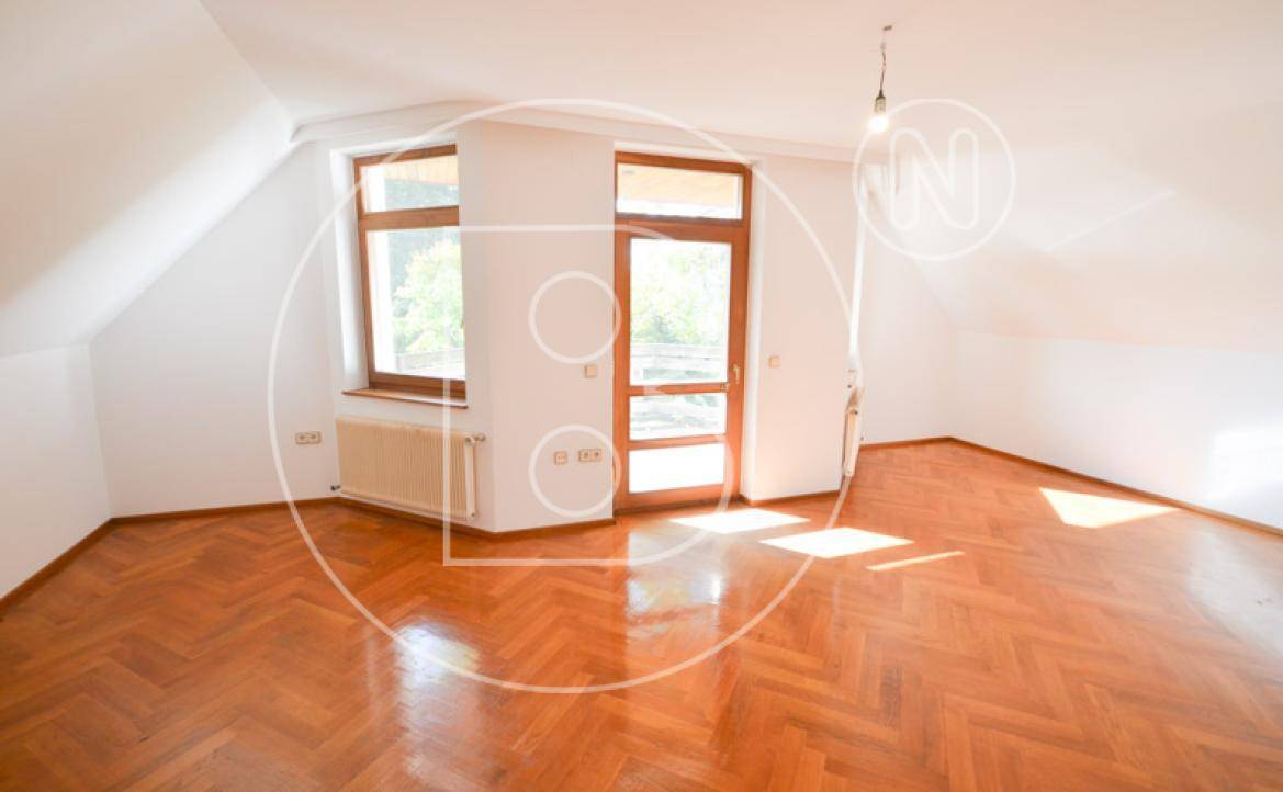 Helles Schlafzimmer im Dachgeschoss mit Fischgrätparkett und Zugang zu einem Balkon.