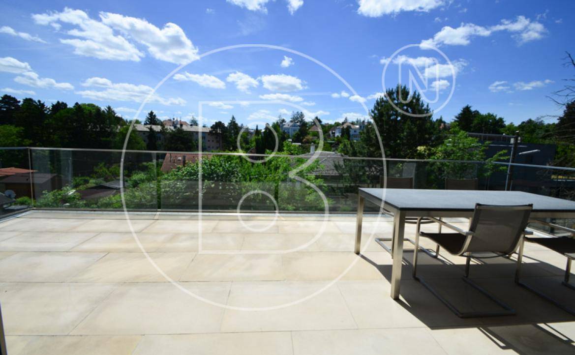 Geräumige Dachterrasse mit Fliesenboden, Glasgeländer und weitem Blick ins Grüne.