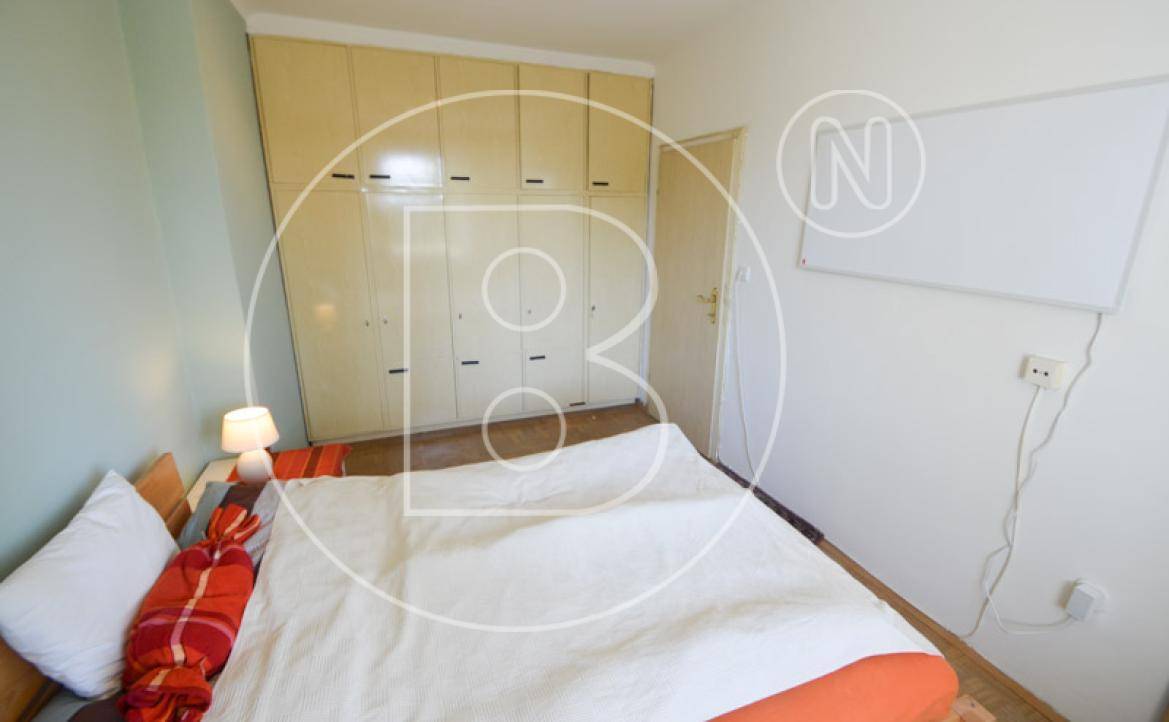 Schlafzimmer mit Einbauschränken, Einzelbett und hellem Fenster, das viel Licht spendet.