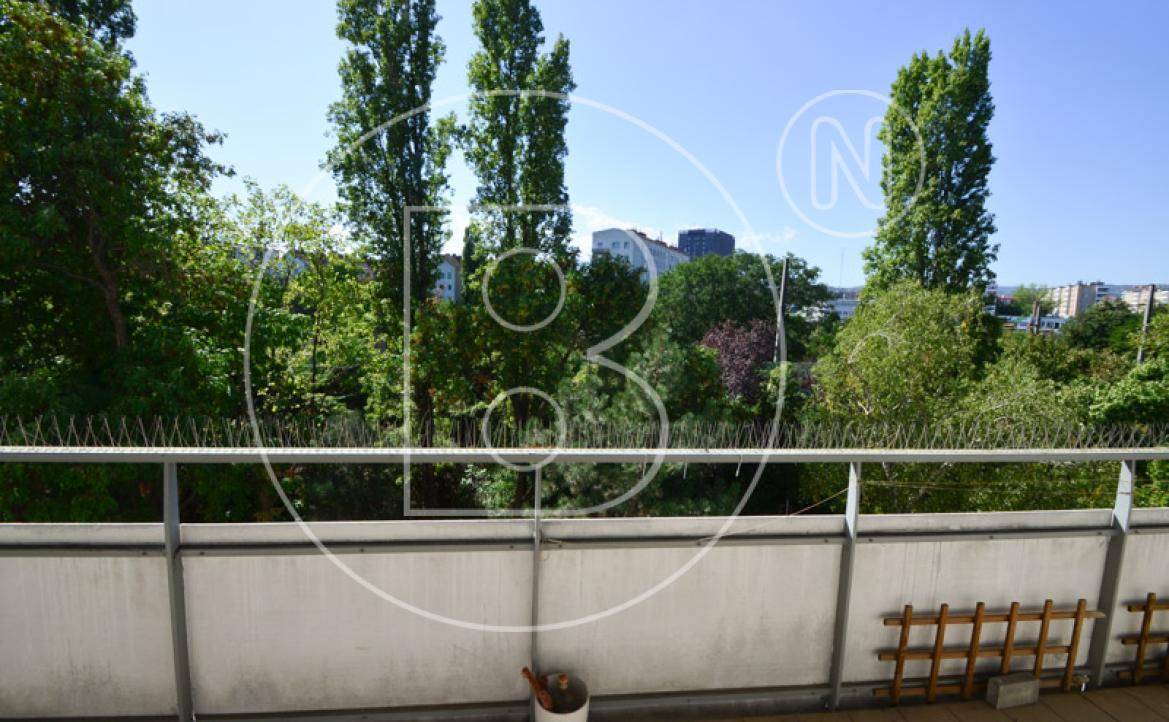 Balkon mit Blick ins Grüne und auf die umliegende Stadtlandschaft unter blauem Himmel.