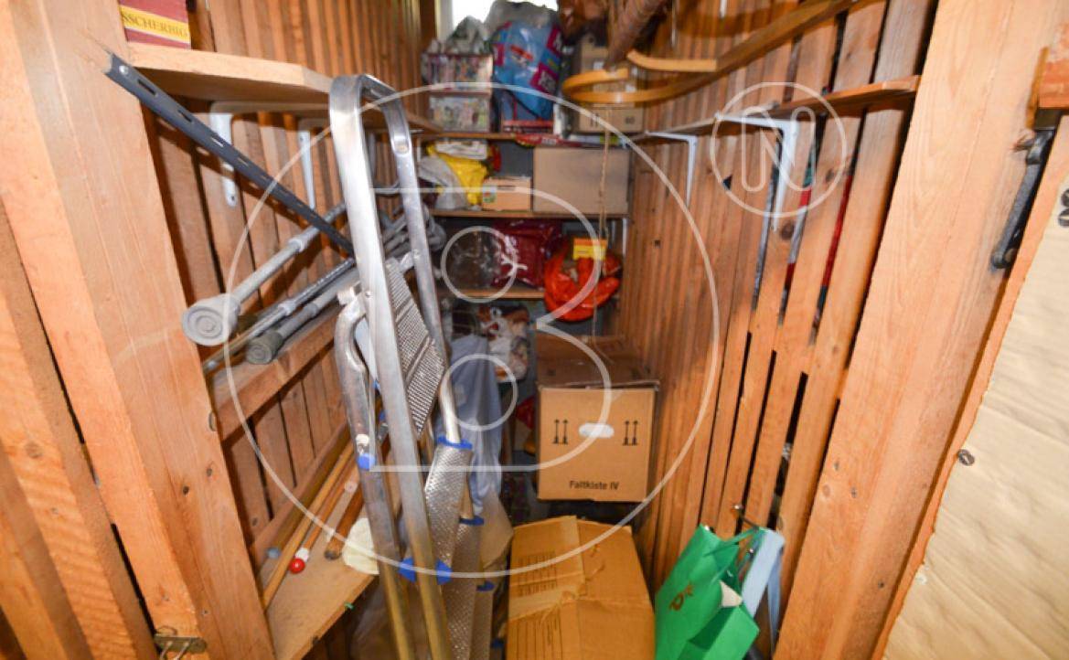 Dachbodenabteil mit Holzverkleidung und Stauraum für diverse Gegenstände und Leitern.
