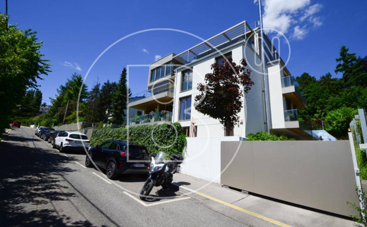 Moderne Wohnanlage mit ansprechender Architektur, großen Fenstern und Balkonen an einer ruhigen Straße.