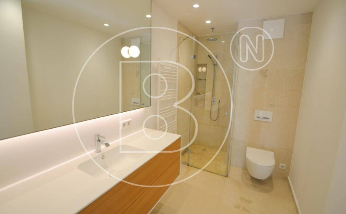Modernes Badezimmer mit Doppelwaschbecken, großer Spiegelfläche, begehbarer Dusche und Wand-WC.