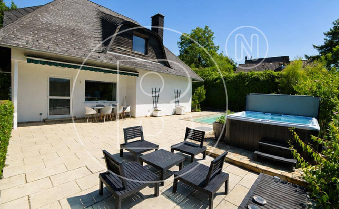 Großzügige Terrasse mit Lounge-Möbeln, Whirlpool und Blick auf den Pool und das Haus.