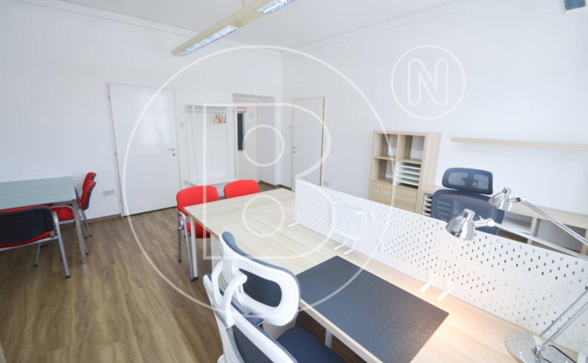 Moderner Büroraum mit mehreren Arbeitsplätzen, Garderobenbereich und hellem Holzfußboden.