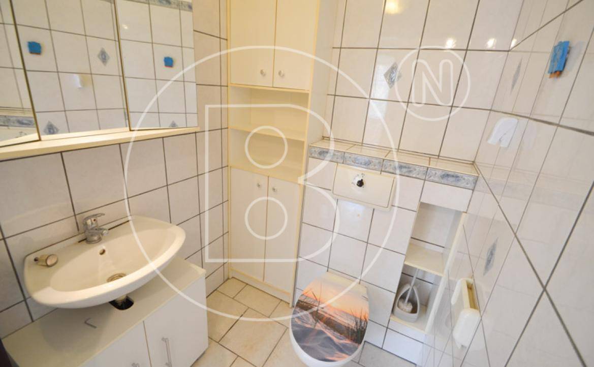 Kleines WC mit weißen Fliesen, Waschbecken und eingebauten Schränken.