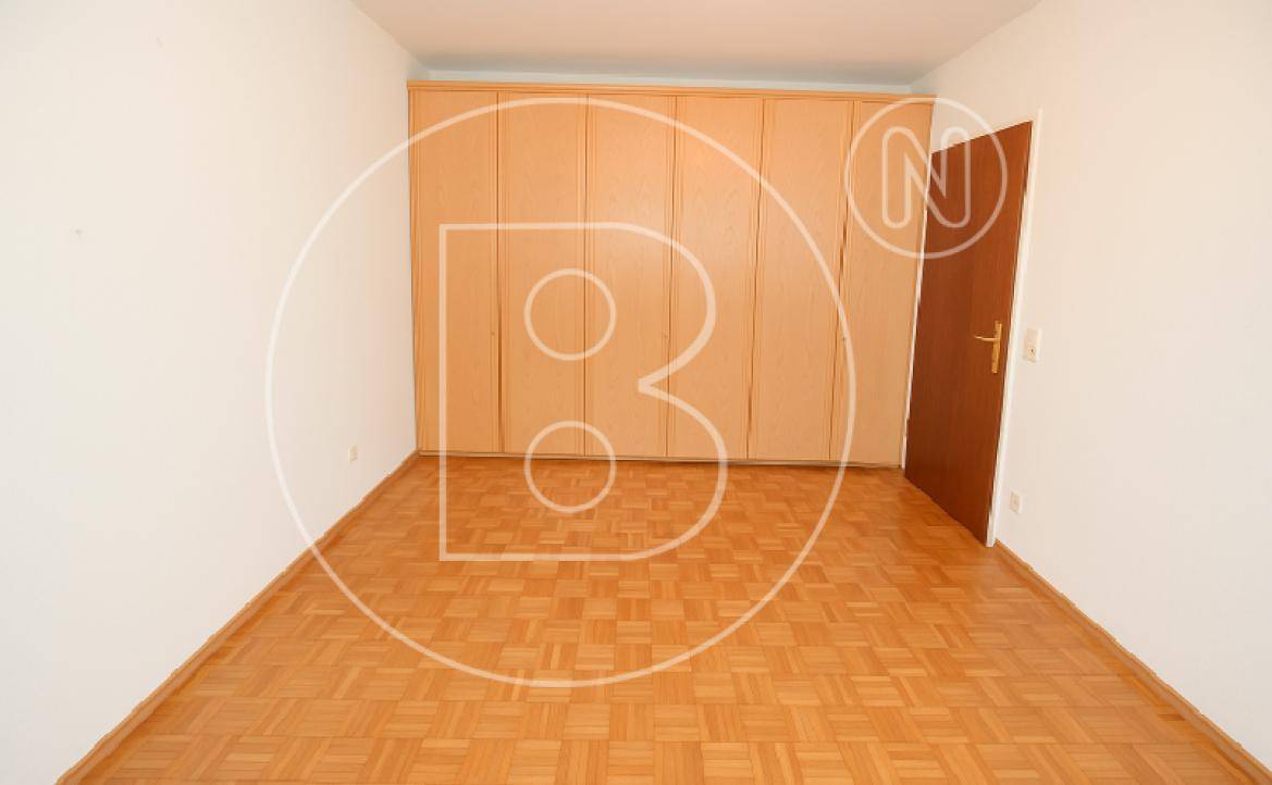 Schlafzimmer mit Parkettboden und praktischen Einbauschränken aus Holz für Stauraum.