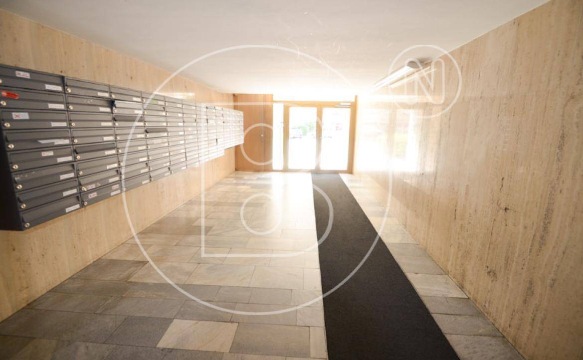 Heller Eingangsbereich mit Briefkästen, Marmorboden und viel Tageslicht durch die Glastür.