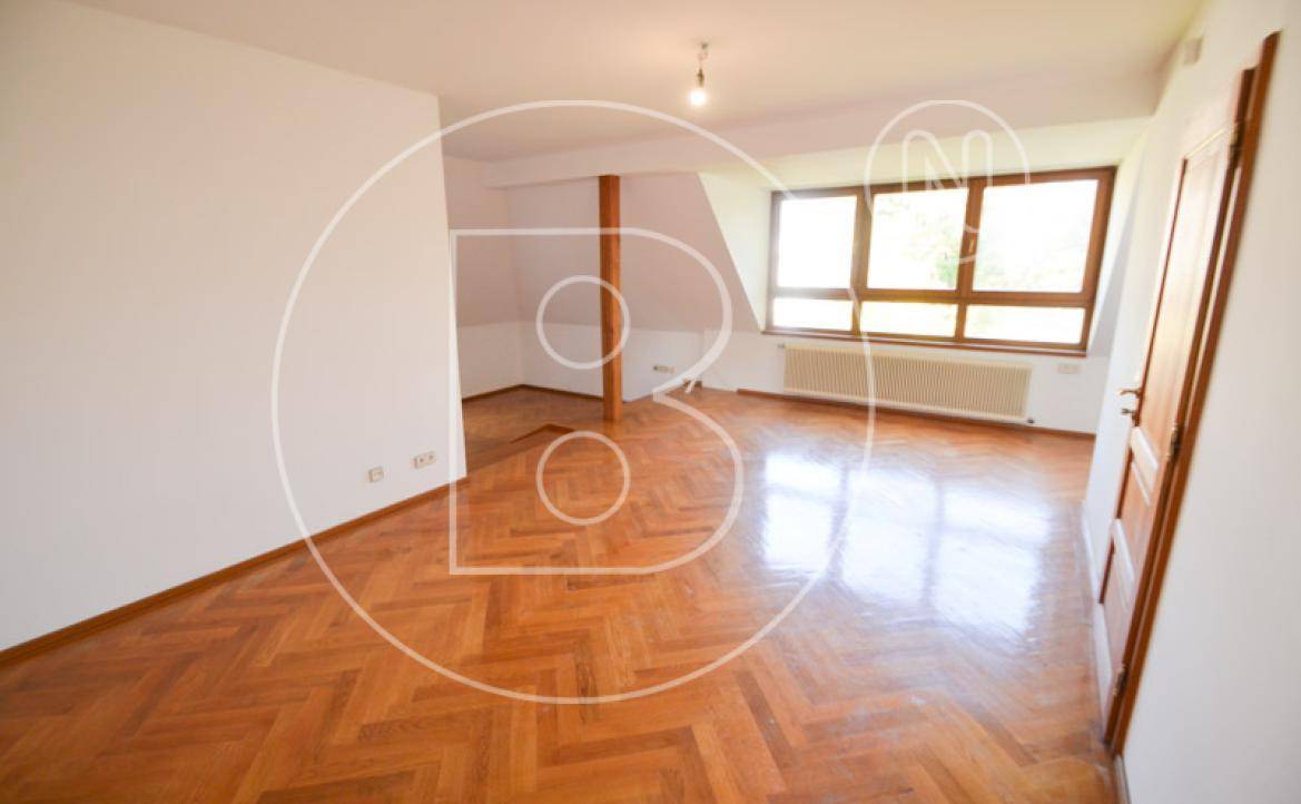 Helles Zimmer im Dachgeschoss mit Parkettboden, großen Fenstern und Dachschrägen.