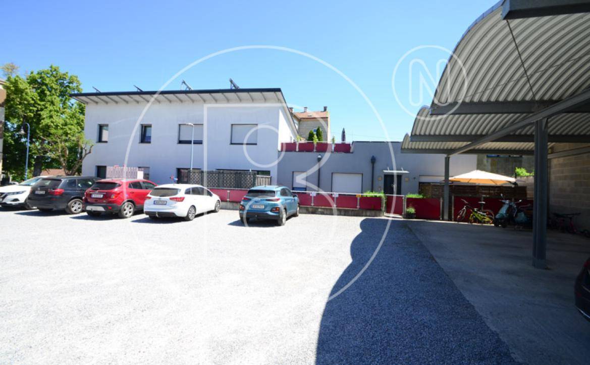 Parkplatz mit überdachten Stellplätzen und angrenzendem Gebäude, bietet Schutz vor Witterung.