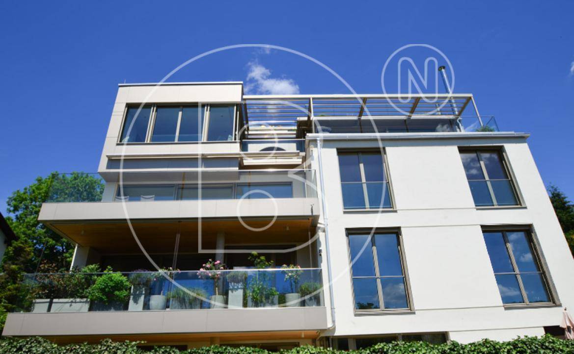 Elegante Fassade eines modernen Wohnhauses mit großzügigen Balkonen und viel Glas.