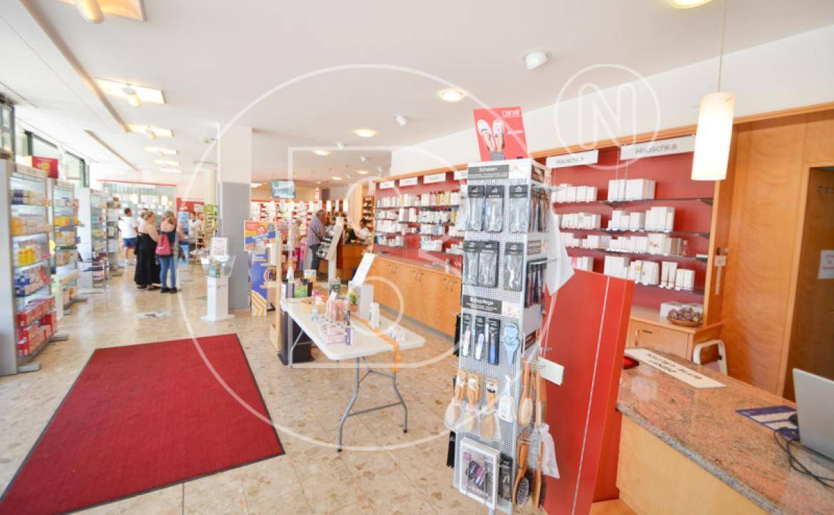 Innenansicht einer Apotheke oder eines Ladens mit Regalen, Produkten und Kunden.