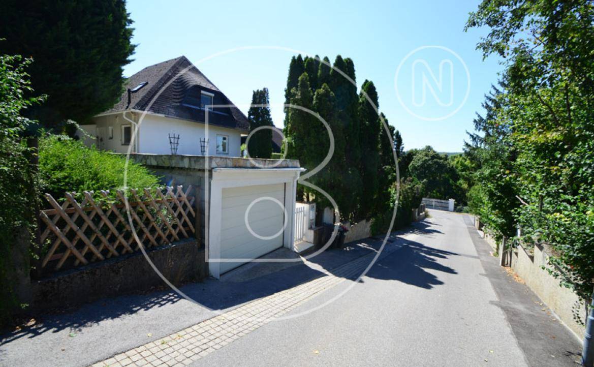 Zufahrt zur Garage von der Straße aus mit dem Haus auf einem Hang im Hintergrund.