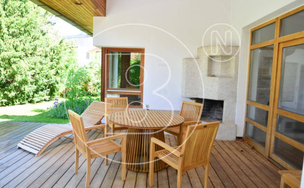 Sonnige Holzterrasse mit Gartenmöbeln und einem Außenkamin für gemütliche Abende.