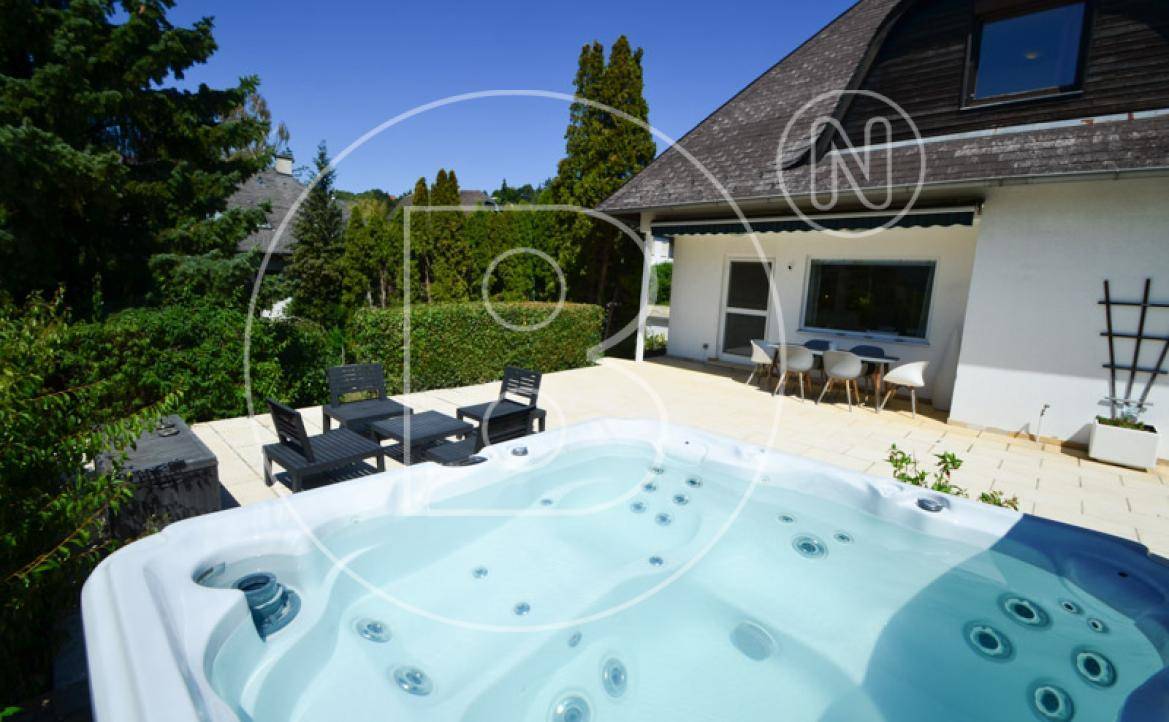 Entspannender Whirlpool auf der sonnigen Terrasse mit weiteren Sitzgelegenheiten und Blick ins Grüne.