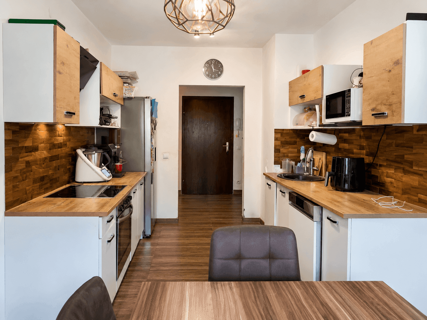 Funktionale Küche mit Holz- und weißen Schränken, Holzarbeitsplatten und modernen Geräten.