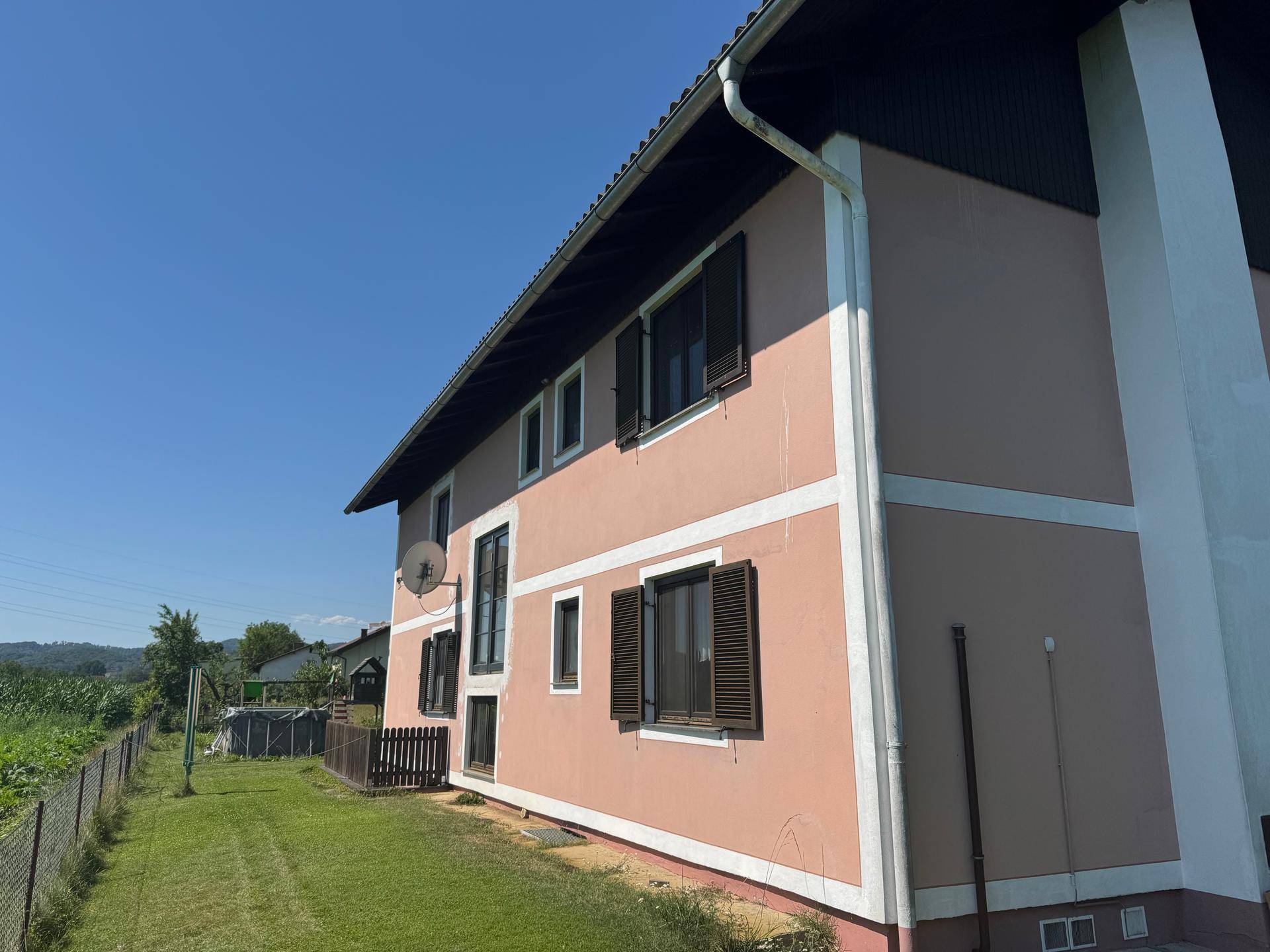 Seitenansicht des Hauses mit Fenstern und einem angrenzenden Gartenbereich.