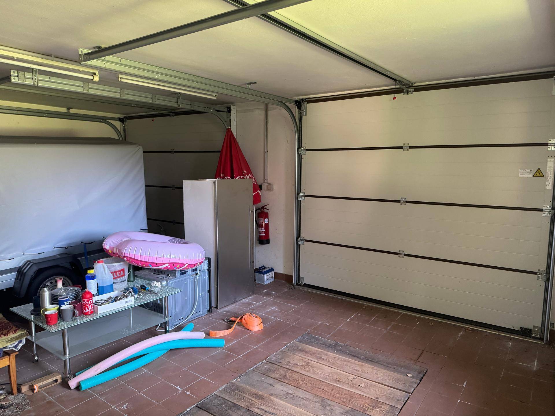 Garage mit Sektionaltor und Stauraum für verschiedene Gegenstände.