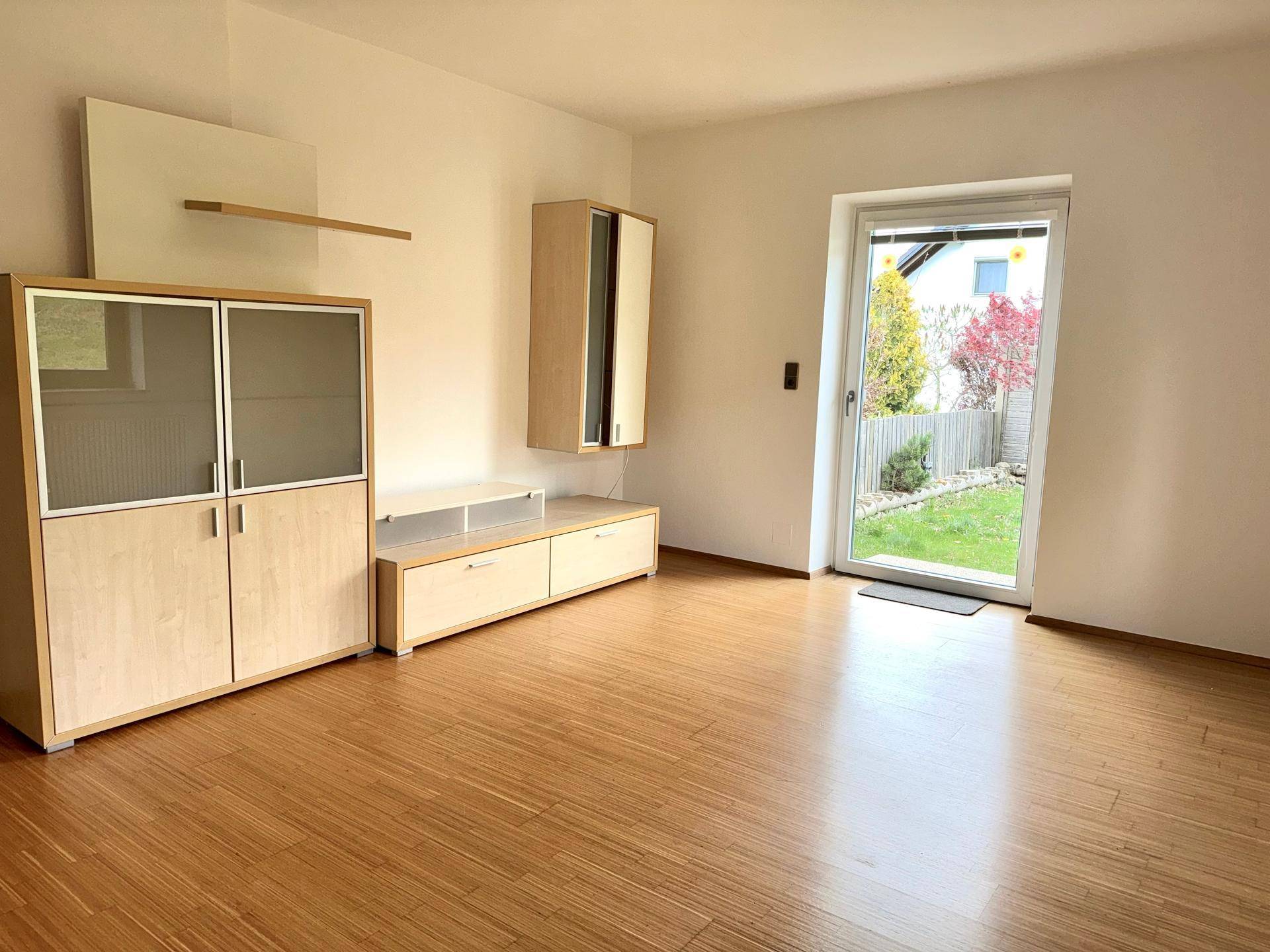 Helles Wohnzimmer mit Holzfußboden, modernen Möbeln und direktem Zugang zum Garten.