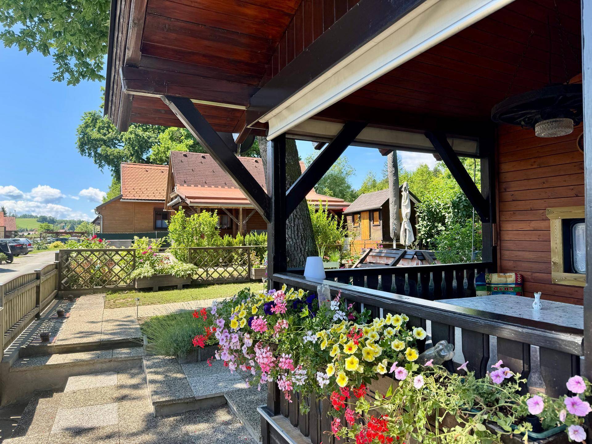 Überdachte Terrasse mit Blumenkästen und Blick auf die umliegende grüne Landschaft.