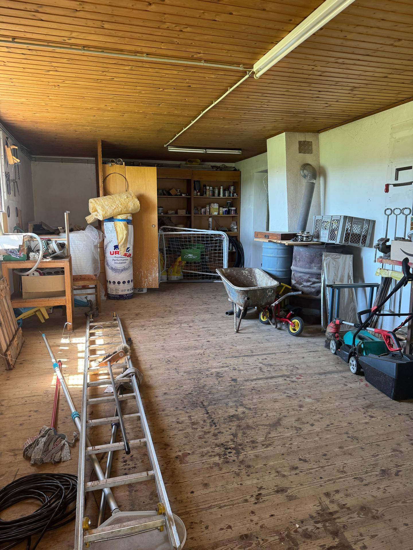 Geräumiger Werkstatt- oder Abstellraum mit Holzdecke und verschiedenen Geräten.