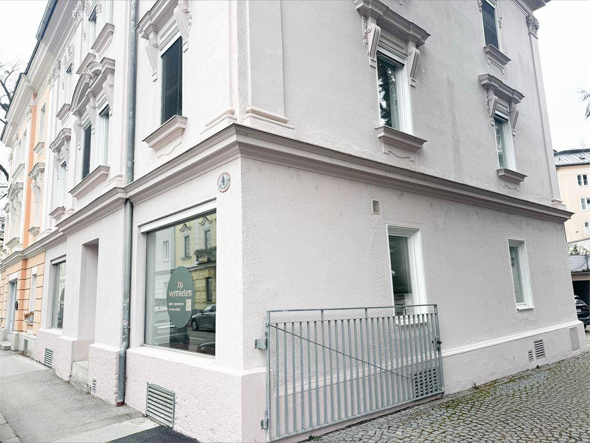 Geräumiger, leerer Büroraum mit hellem Holzfußboden, weißen Wänden und großen Fenstern für viel Tageslicht.
